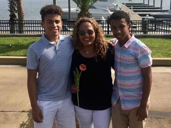 caption: Rocio Tirado, who works for a New Orleans area newspaper, has seen her pay drop during the pandemic. She asked her sons Nicholas (left) and Emilio to be less wasteful.