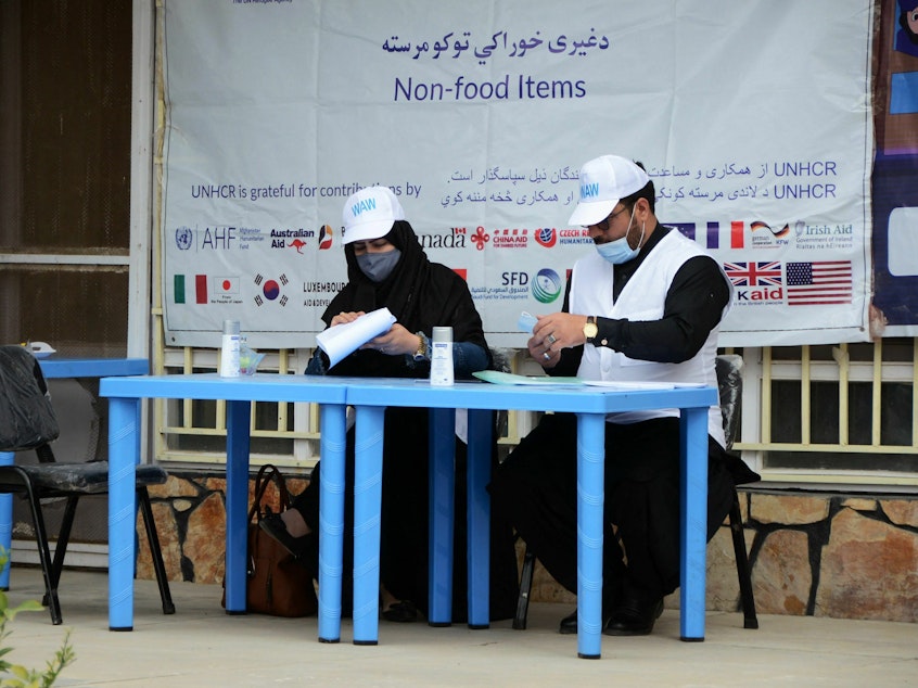 caption: United Nations High Commissioner for Refugees workers prepare to distribute non-food items to women at UNHCR office in Kandahar on March 8, 2022. The Taliban has demanded that Afghan women no longer work for the UN or NGOs.
