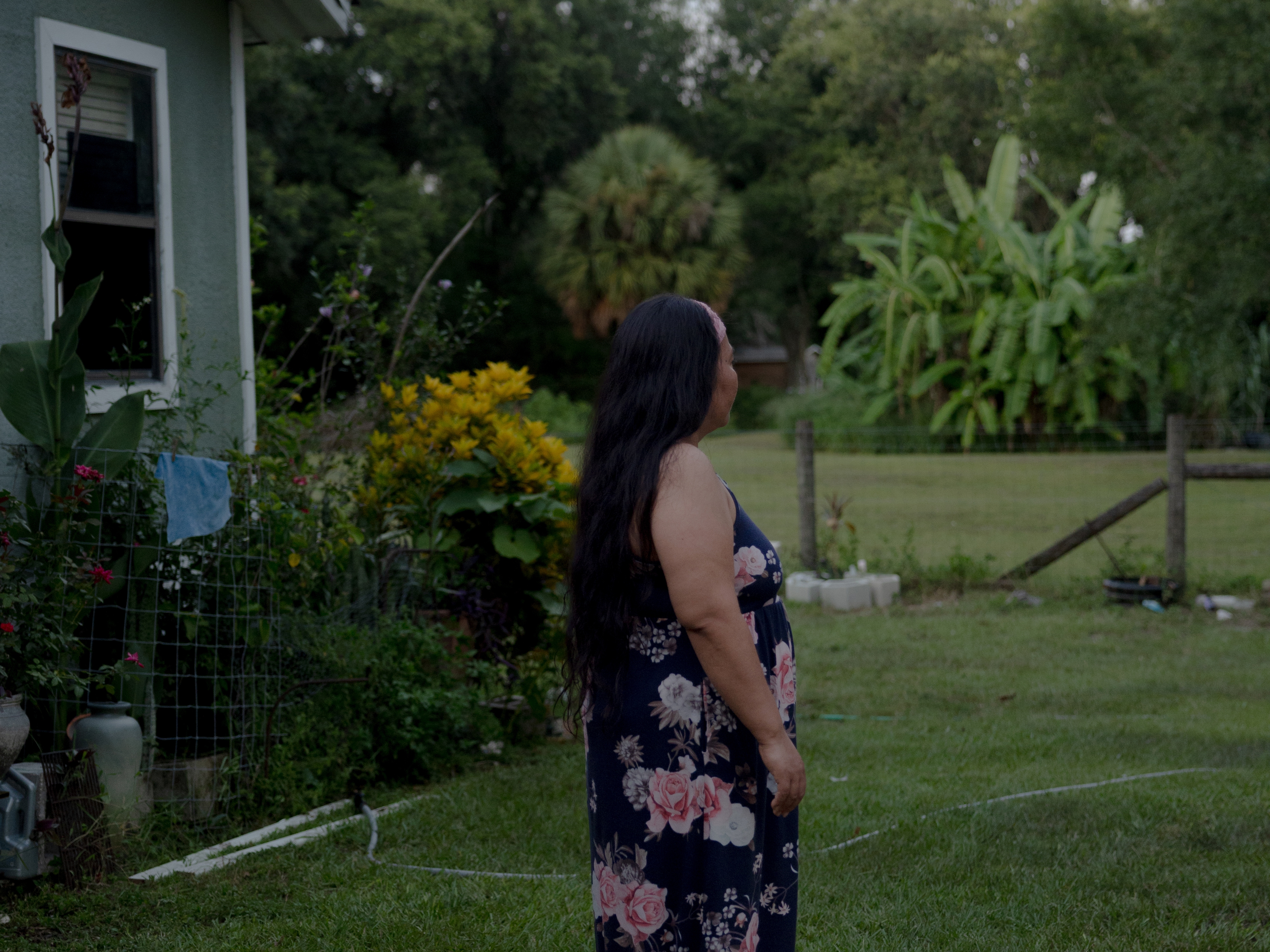 caption: A woman poses for a portrait outside her home, Saturday, July 19, 2025, in Tampa. Her family are discussing emergency plans if she or her husband were to be detained, and are looking to move to another state where the police presence is less felt. 

(Lexi Parra for NPR)