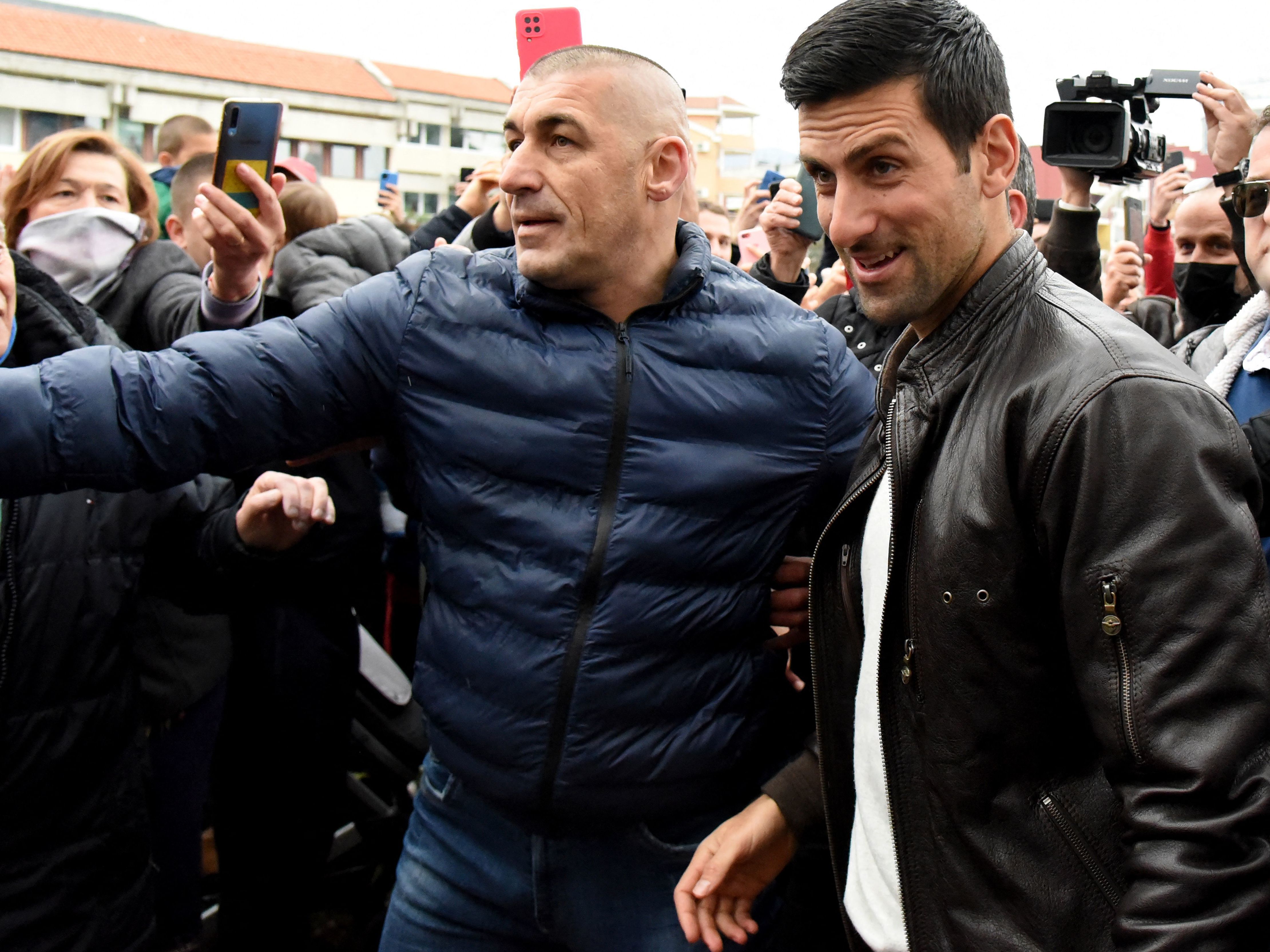 caption: Serbian tennis player Novak Djokovic, right, walks surrounded by fans as he arrives for a ceremony in the coastal city of Budva, Montenegro, on Jan. 28. In a new interview, he says he'd rather skip tournaments like the French Open than get the COVID vaccine.