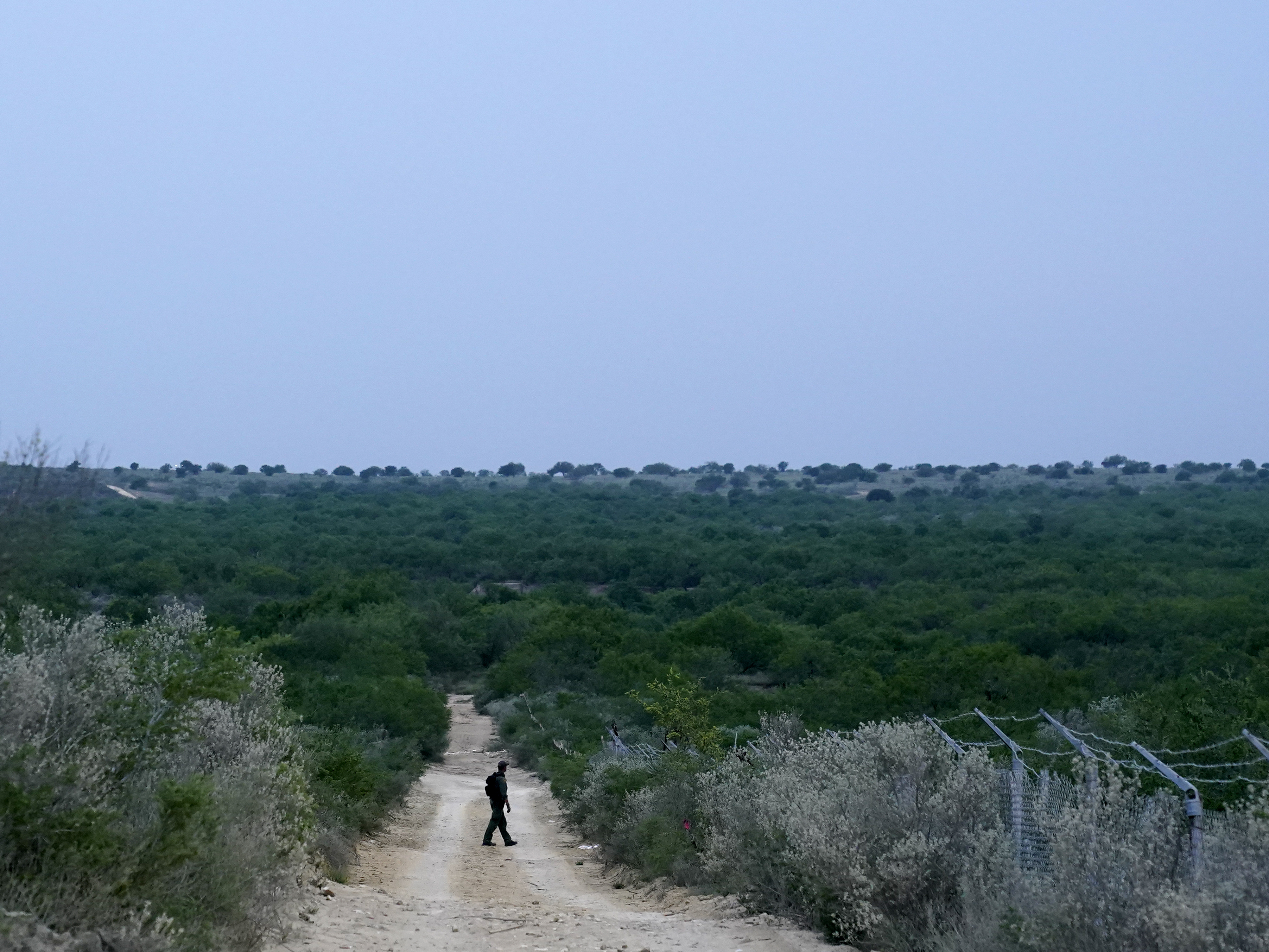 caption: A Border Patrol agent walks along a dirt road near the U.S.-Mexico border, in Roma, Texas, in May.