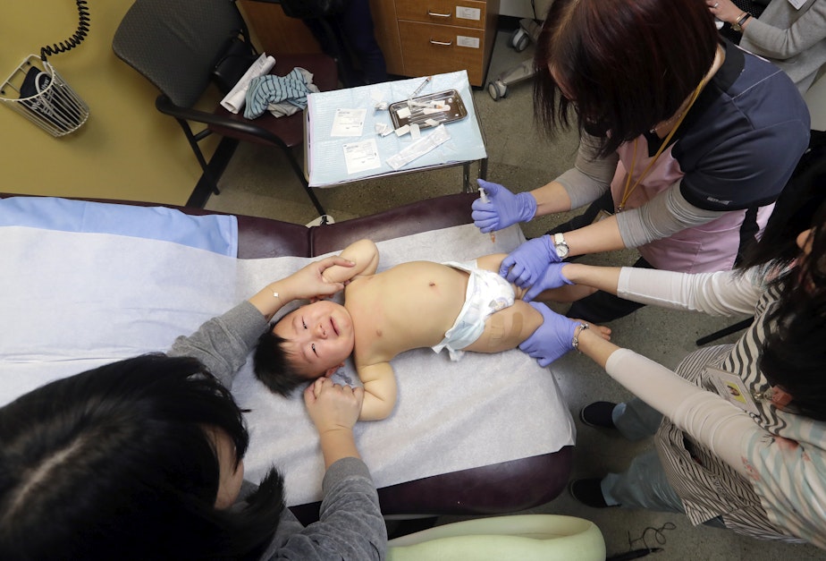 caption: One-year-old Abel Zhang receives the last of three inoculations, including a vaccine for measles, mumps, and rubella (MMR), at the International Community Health Services Wednesday, Feb. 13, 2019, in Seattle.