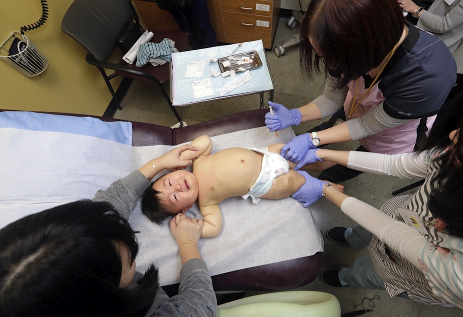caption: One-year-old Abel Zhang receives the last of three inoculations, including a vaccine for measles, mumps, and rubella (MMR), at the International Community Health Services Wednesday, Feb. 13, 2019, in Seattle.