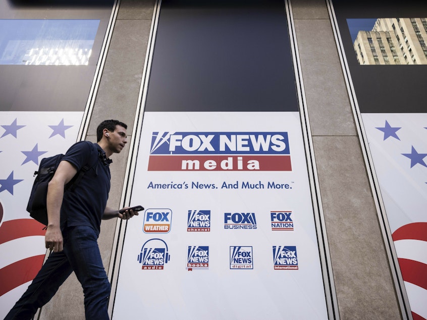 caption: A person walks past the Fox News Headquarters in New York on April 12.