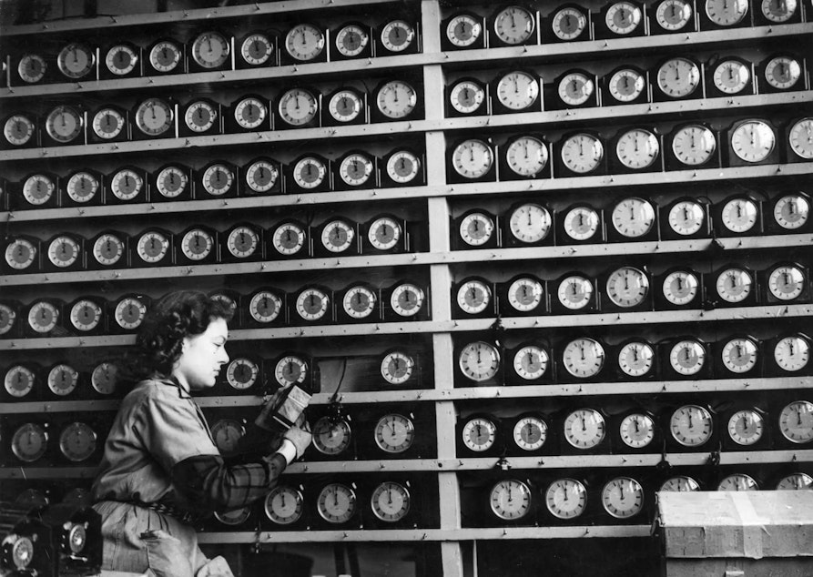 caption: The timesinks, they are a changin’. Above, a woman checks alarm clocks in a London clock factory in 1946.

