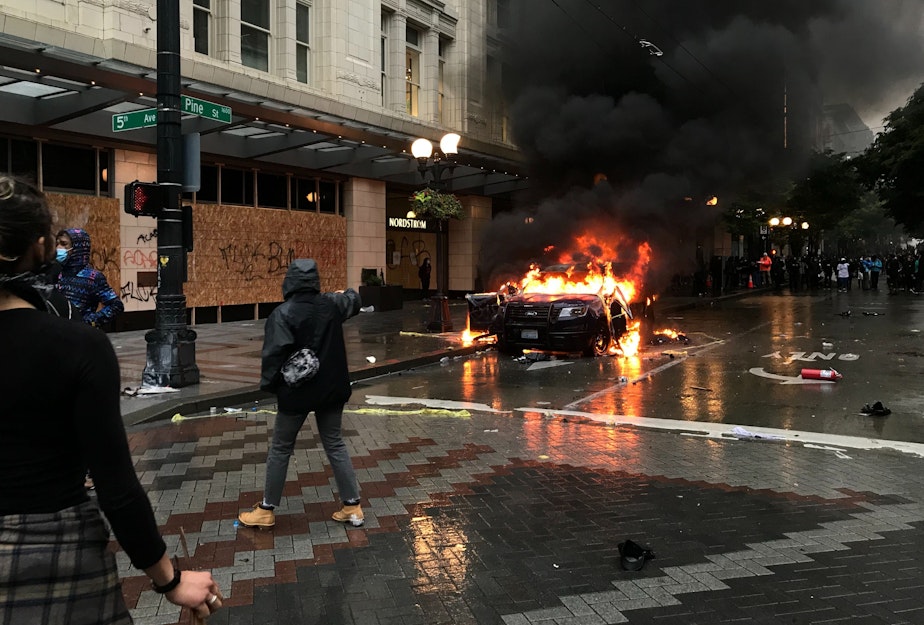 caption: A police car burns outside the Nordstrom in downtown Seattle on Saturday, May 30, 2020.