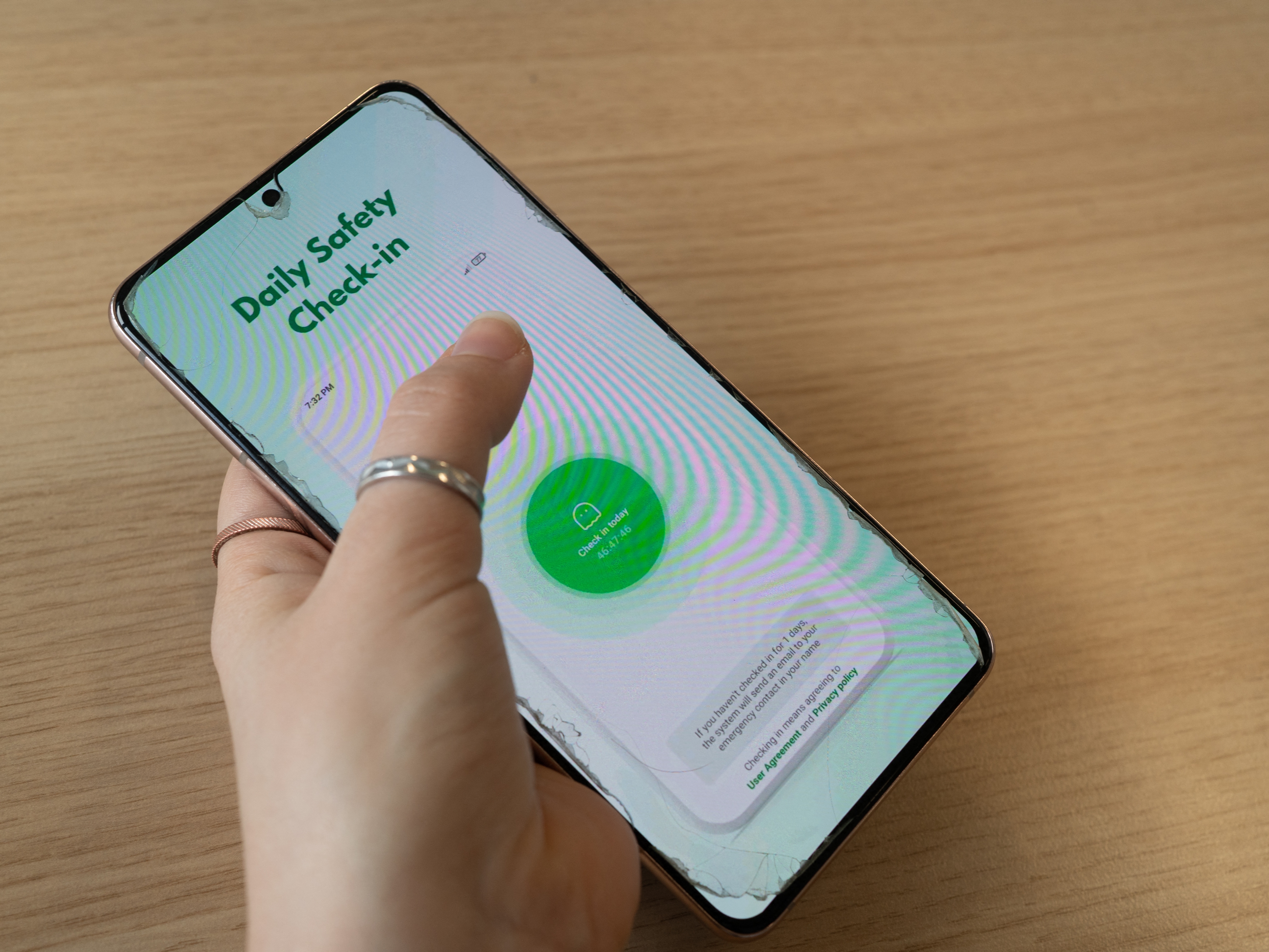 caption: A person holds a phone that displays the "Are You Dead?" app in Paris on Jan. 22.