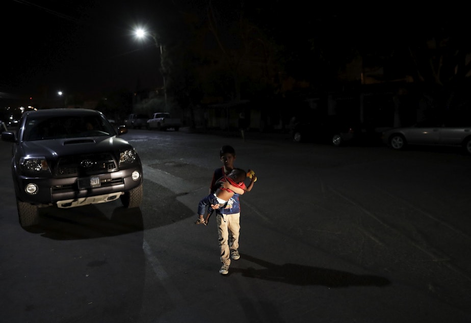 caption: Juan Munoz, of Tijuana, Mexico, carries 2-year-old Haitian migrant Juandele at a shelter for migrants on their way to the United States on Monday, Nov. 14, in Tijuana, Mexico.