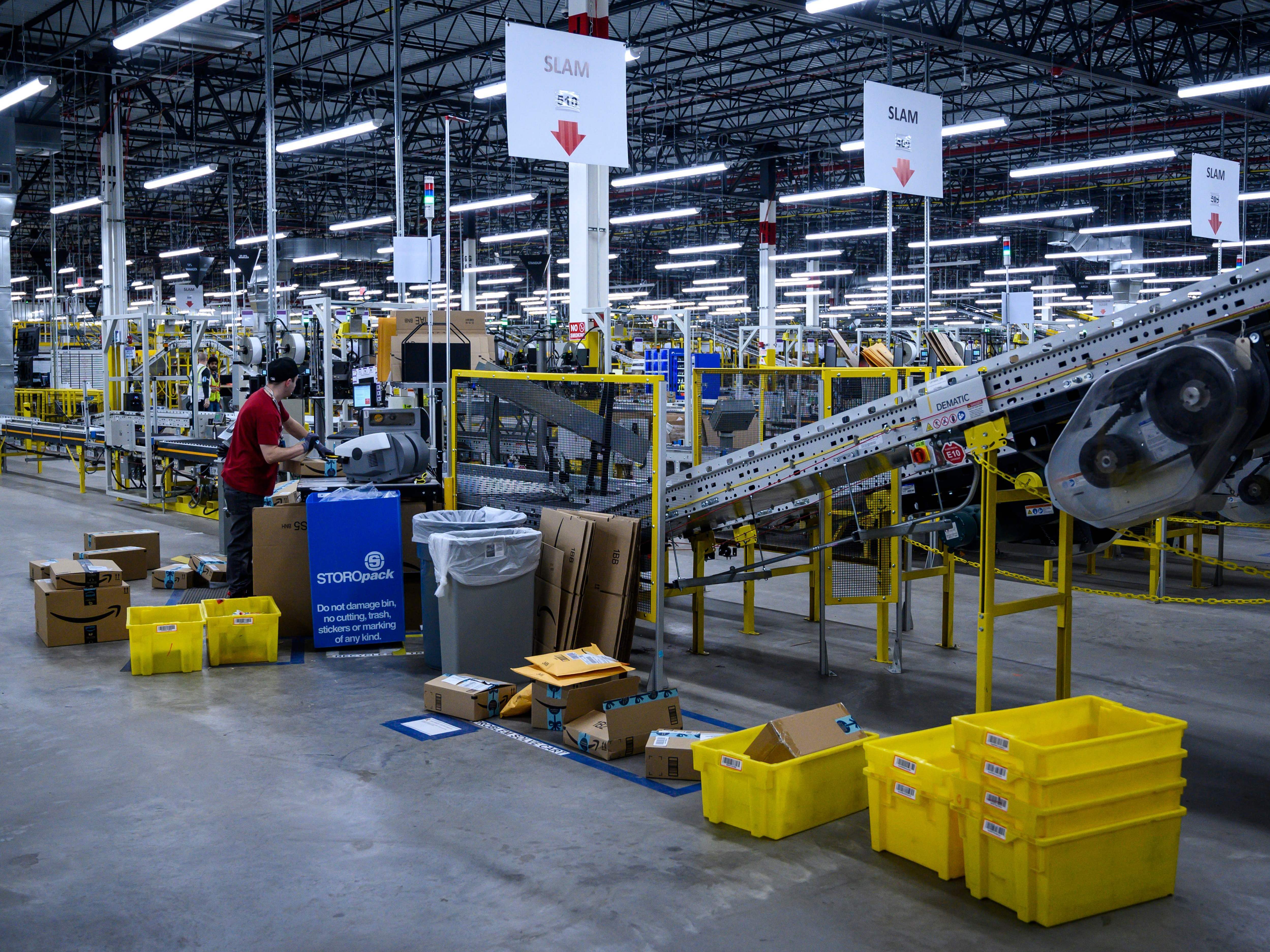 caption: A man works at a conveyor belt at the 855,000-square-foot Amazon warehouse in New York in 2019.