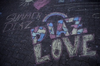 caption: Chalk drawings are shown next to a memorial for Summer Taylor and Diaz Love on Wednesday, July 22, 2020, at City Hall Park in Seattle. 