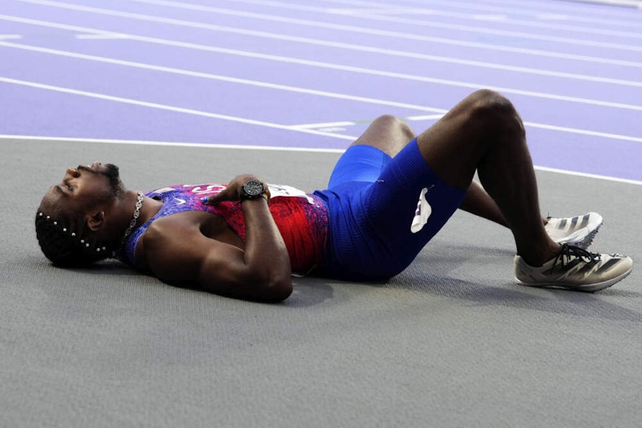 caption: Noah Lyles, of the United States, lies on the track following the men's 200-meters final. Lyles said he tested positive for COVID two days before he finished third in the 200-meter final. (Petr David Josek/AP)