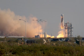 caption: The New Shepard Blue Origin rocket lifts-off from the launch pad carrying Jeff Bezos along with his brother Mark Bezos, 18-year-old Oliver Daemen, and 82-year-old Wally Funk prepare to launch on Tuesday in Van Horn, Texas. The crew are riding in the first human spaceflight for the company.