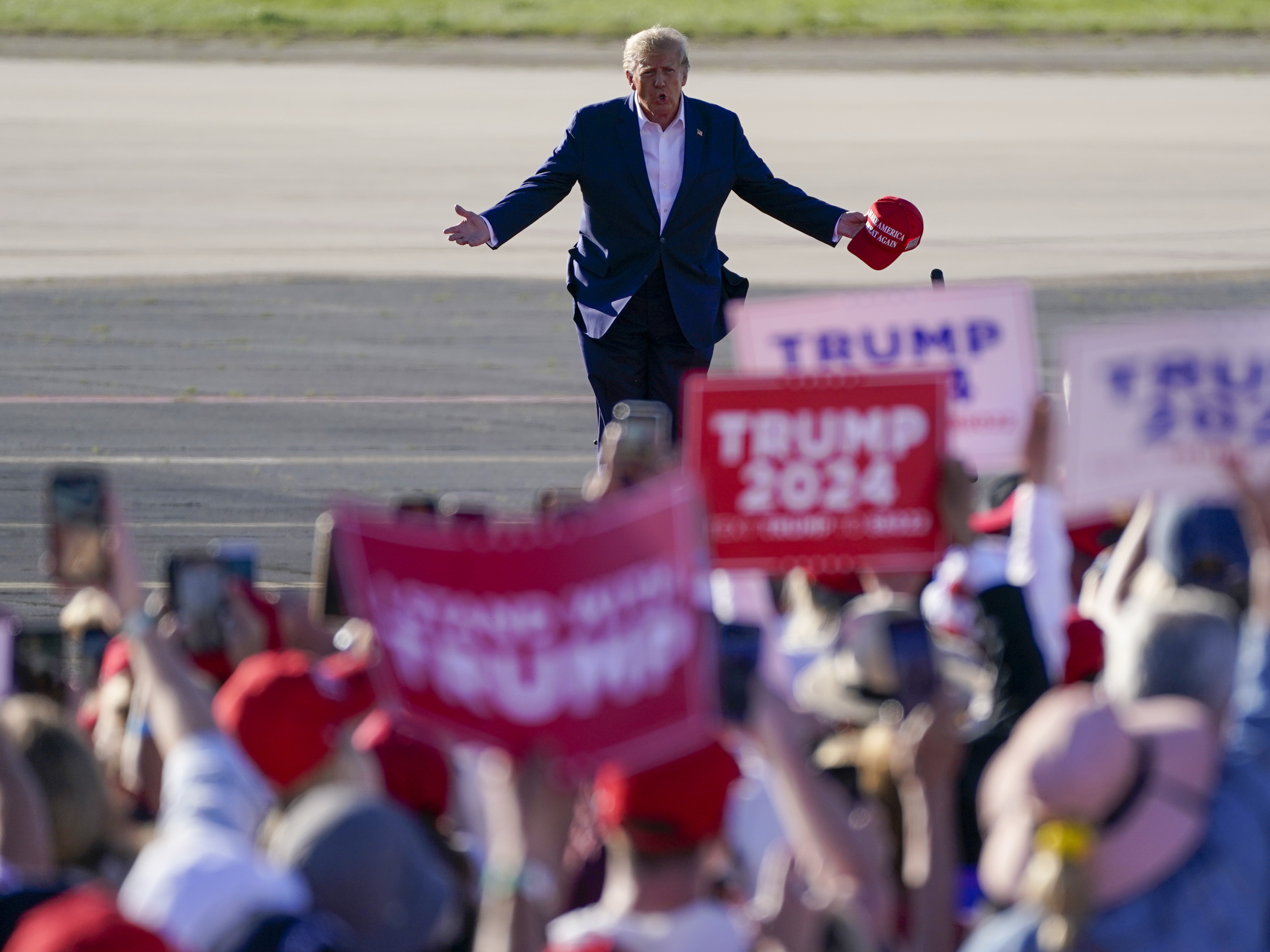caption: Former President Donald Trump walks across the tarmac as he arrives to speak at a campaign rally at Waco Regional Airport on March 25, 2023, in Waco, Texas.
