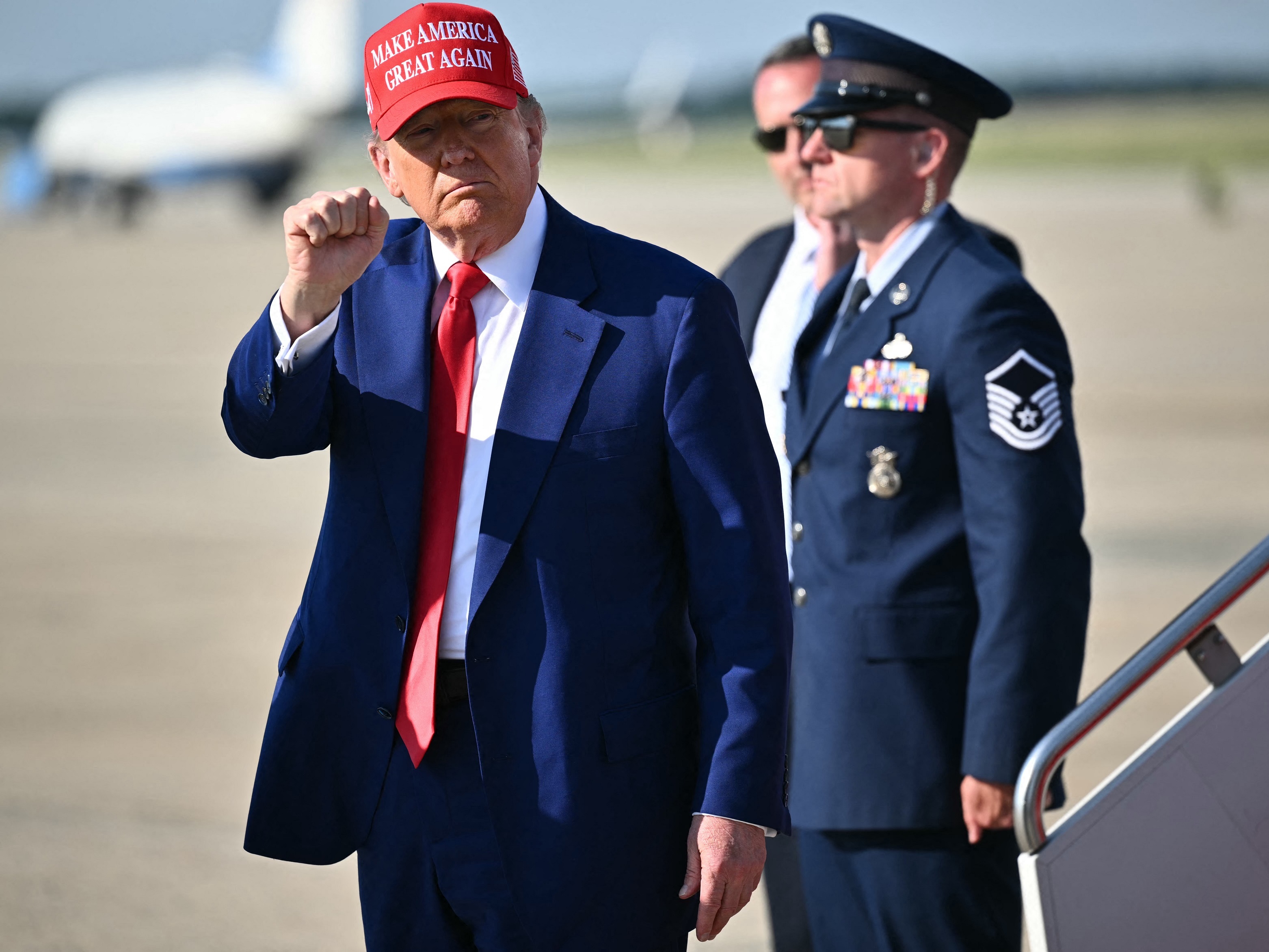 caption: President Trump pumps his fist after stepping off Air Force One at Joint Base Andrews in Maryland on Saturday.