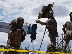 caption: A sculpture of Juan de Onate's group of settlers colonizing New Mexico is pictured as workers for the City of Albuquerque remove a sculpture of Spanish conquistador Juan de Onate on Wednesday in Albuquerque, New Mexico. A man was shot a day before as a heavily armed militia group attempted to defend the statue from US protestors in New Mexico.