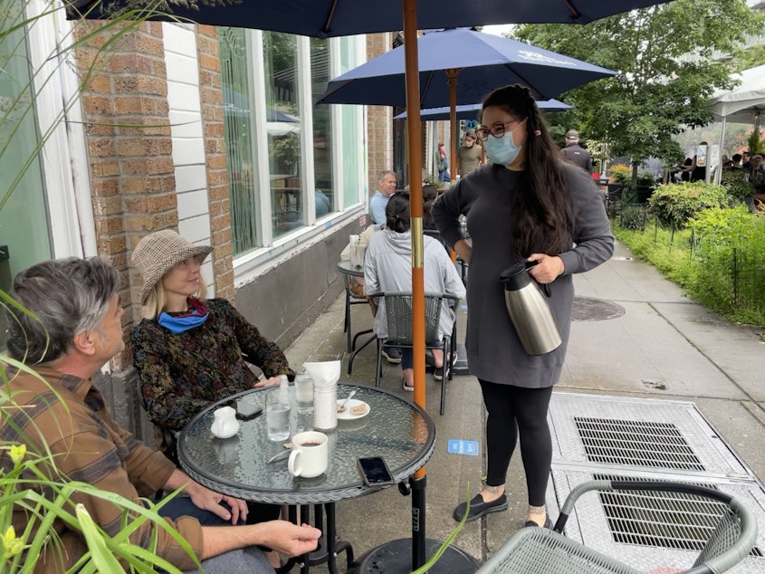 caption: Miki Sodos chats with customers outside Cafe Pettirosso on Capitol Hill in Seattle