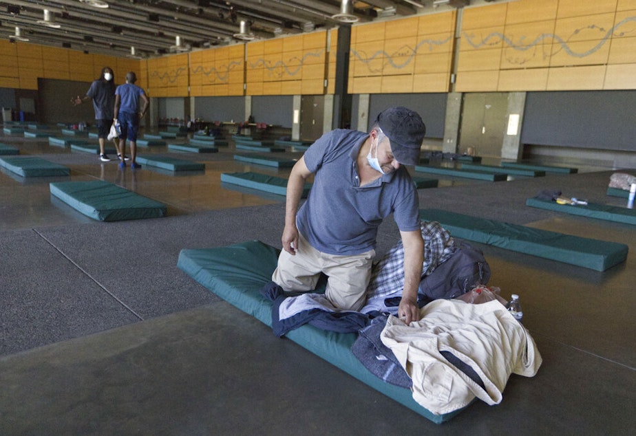 caption: Roberto Cedomio prepares his bed at a cooling shelter run by the Salvation Army at the Seattle Center during a heat wave hitting the Pacific Northwest, Sunday, June 27, 2021, in Seattle. Yesterday set a record high for the day with more record highs expected today and Monday. Cedomio said he was glad to have this place available in the heat. 