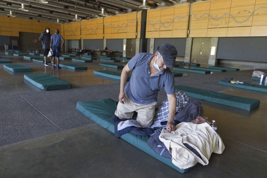 caption: Roberto Cedomio prepares his bed at a cooling shelter run by the Salvation Army at the Seattle Center during a heat wave hitting the Pacific Northwest, Sunday, June 27, 2021, in Seattle. Seattle set a record high for the day with more record highs expected today and Monday. Cedomio said he was glad to have this place available in the heat. 