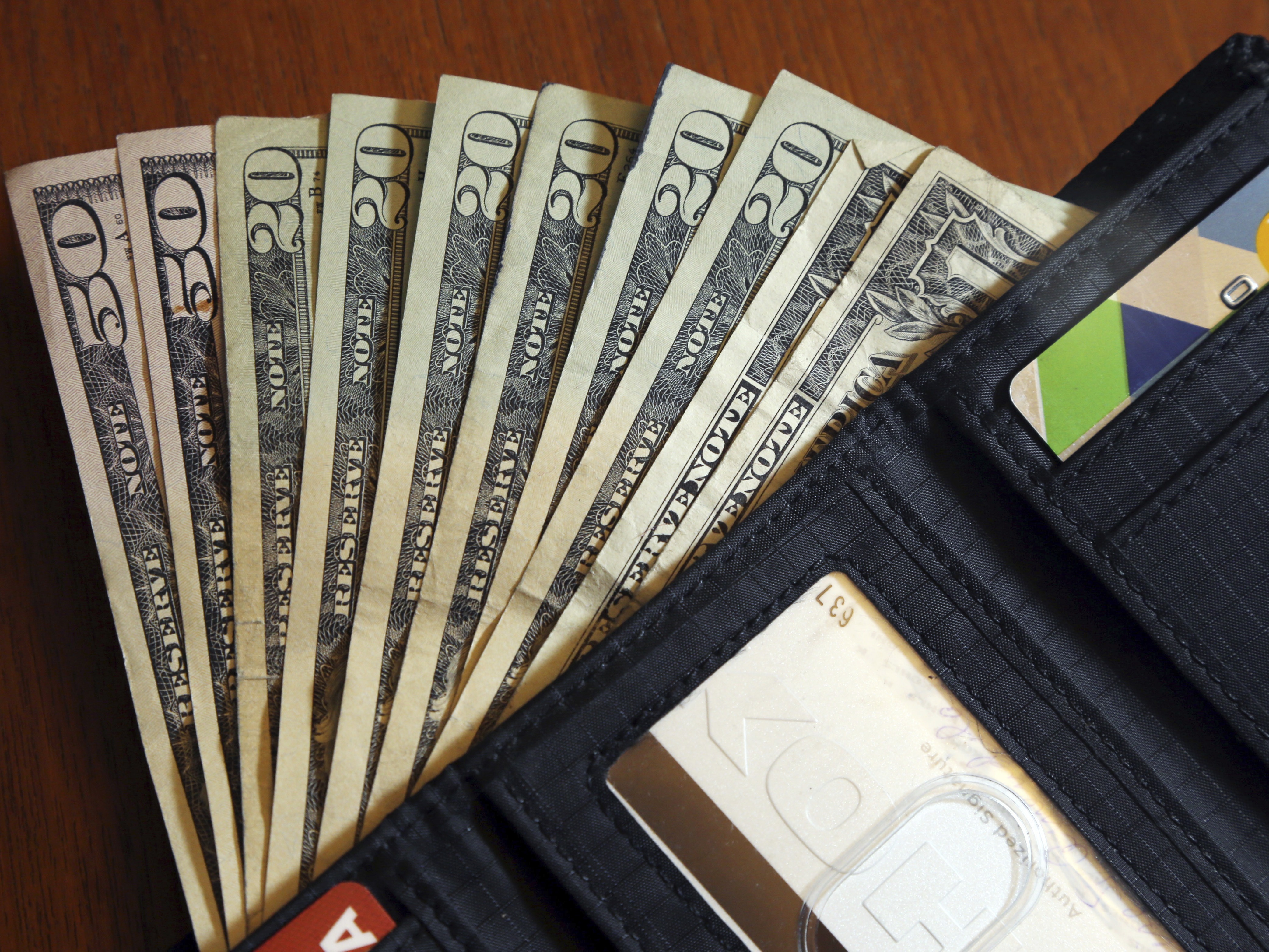 caption: In this June 15, 2018, file photo, cash is fanned out from a wallet in North Andover, Mass.