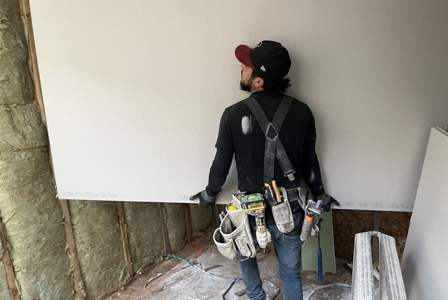 caption: A worker installs sheetrock in a South Seattle townhome in February, 2025.