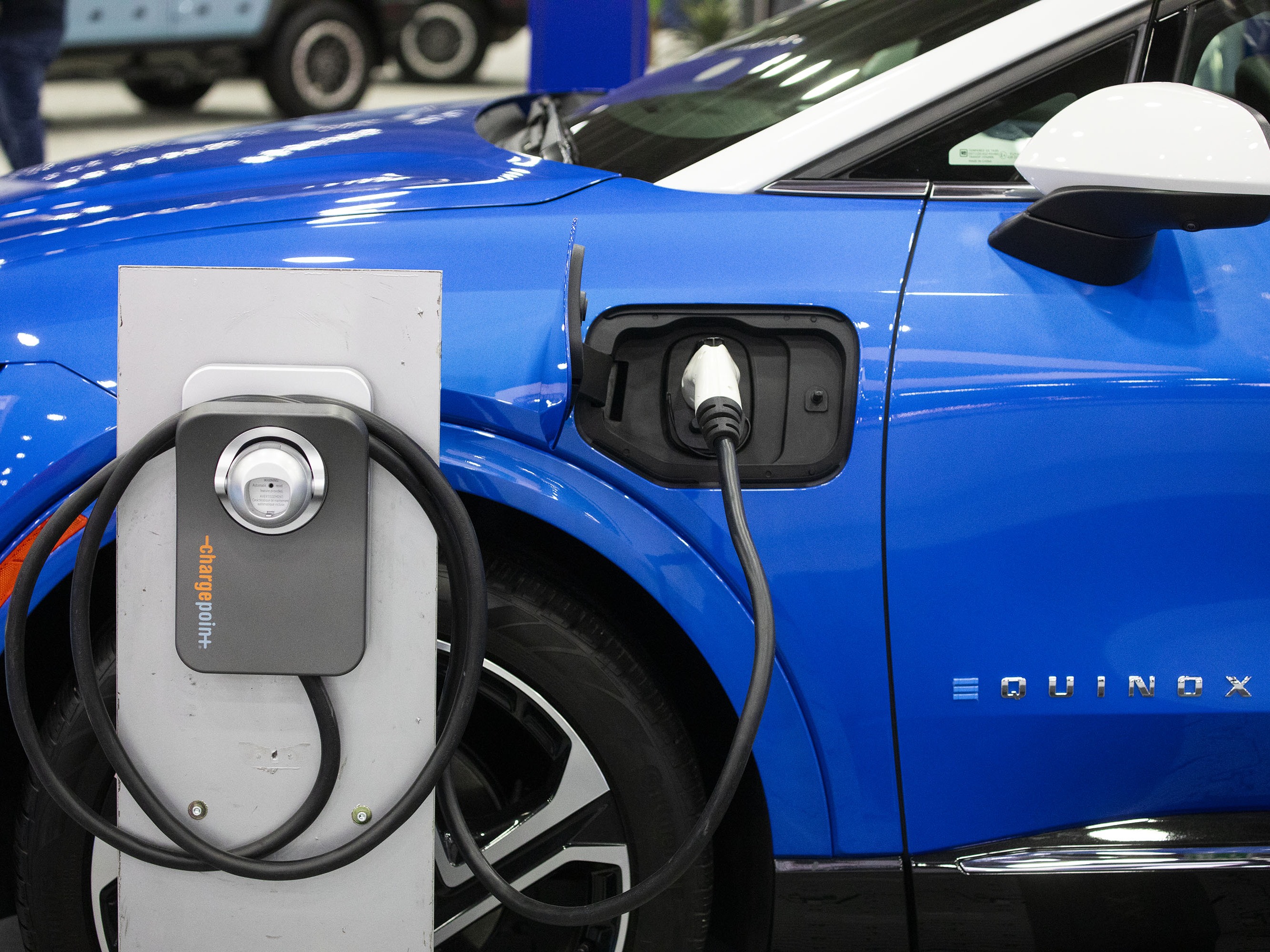 caption: A Powering Michigan display about electric vehicles and charging is shown at the 2025 Detroit Auto Show on Jan. 10. The Biden administration promoted electric vehicles through a range of policies, which the Trump administration is in the process of reversing.