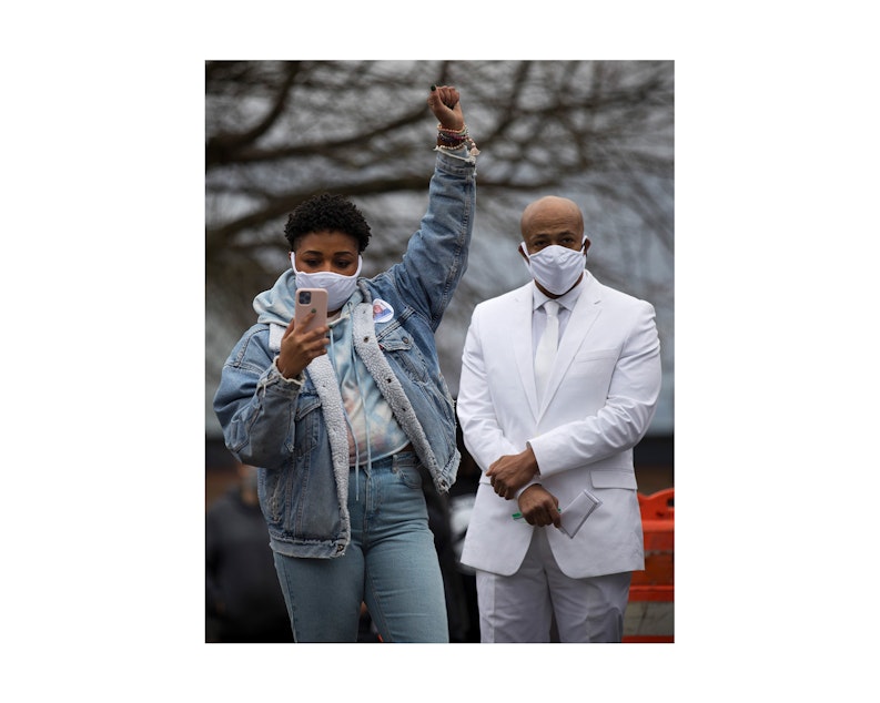 caption: Passia A.C. left, raises a fist in the air while listening to Reverend Dr. Leslie Braxton (not pictured) speak to the crowd, along with the Ellis family's attorney, James Bible, right, following a silent march honoring 33-year-old Manuel Ellis who was killed by Tacoma police, at People's Park along Martin Luther King Jr. Way on Sunday, February 28, 2021, in Tacoma.