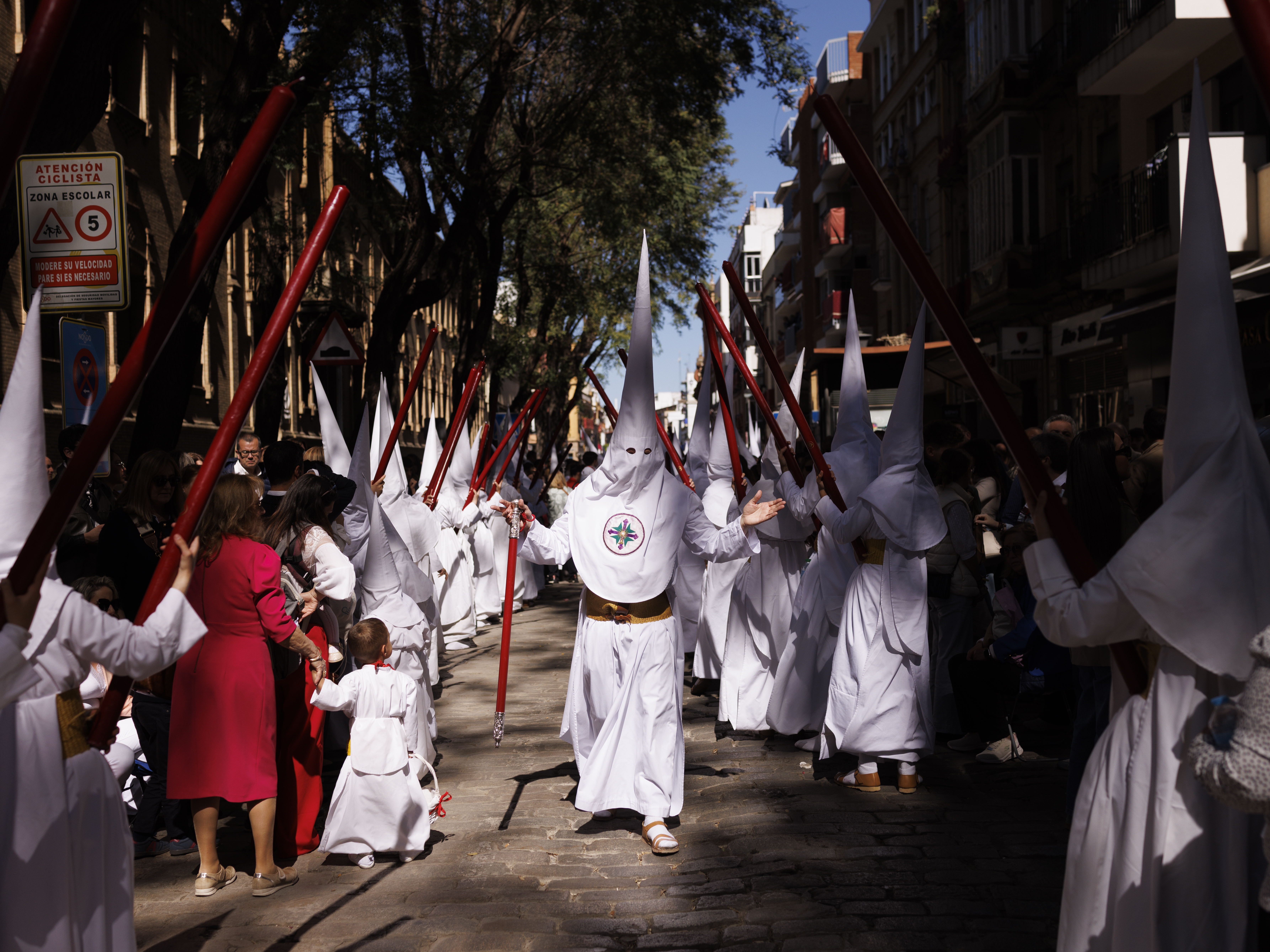 caption: Penitents from the La Paz brotherhood parade in the Palm Sunday procession in Seville, Spain, on March 29. Many of the participants in Semana Santa processions wear traditional costumes that include pointy hoods, which, especially for Americans, may be reminiscent of the Ku Klux Klan. But this Catholic garb far predates the American hate group.