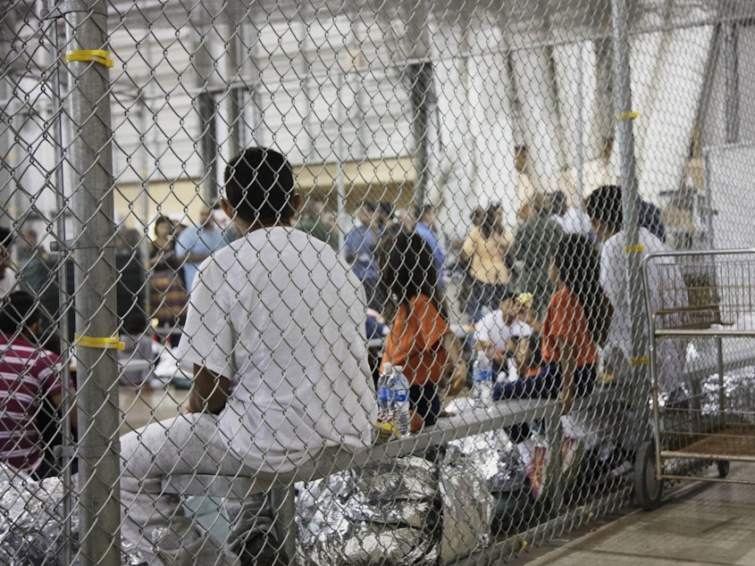 caption: Migrants taken into custody related to cases of illegal entry into the United States sit in a facility in McAllen, Texas, in June 2018. On Tuesday, a federal judge ruled that asylum-seeking migrants can't be denied bond and held indefinitely.