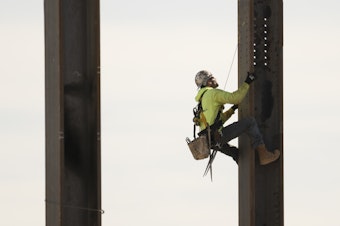 caption: An ironworker scales a column during construction of a municipal building in Norristown, Pa. on Feb. 15, 2023.