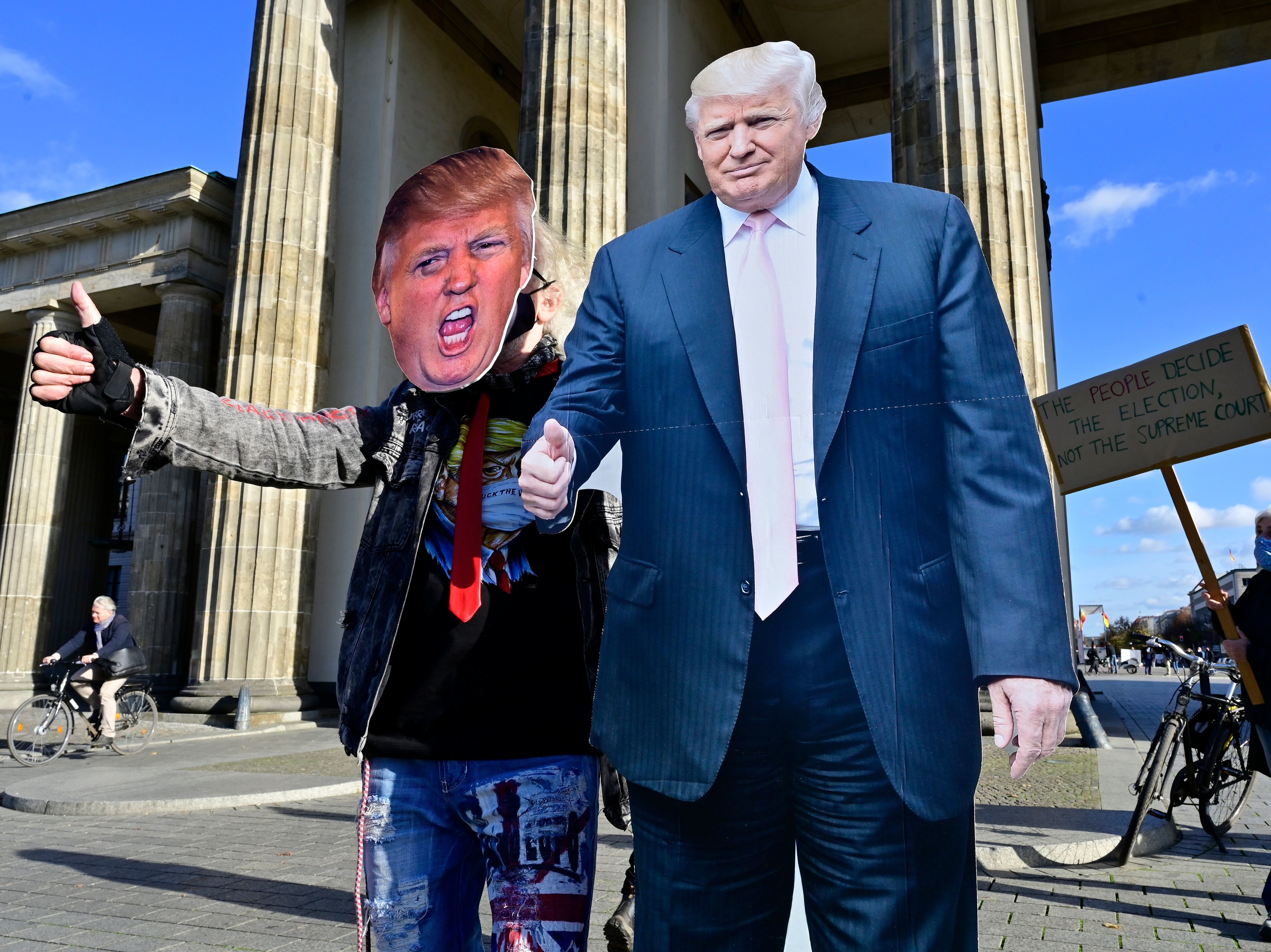 caption: A supporter of President Trump poses with a cardboard cutout likeness in front of the Brandenburg Gate, in Berlin on Wednesday.