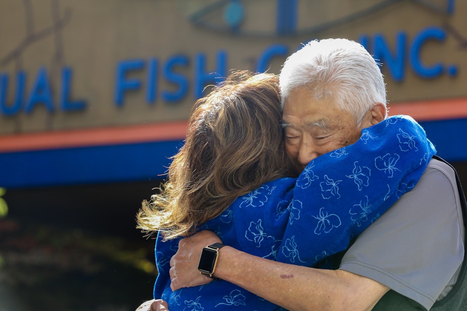caption: Mutual Fish Co. owner hugs a customer in front of the business. 
