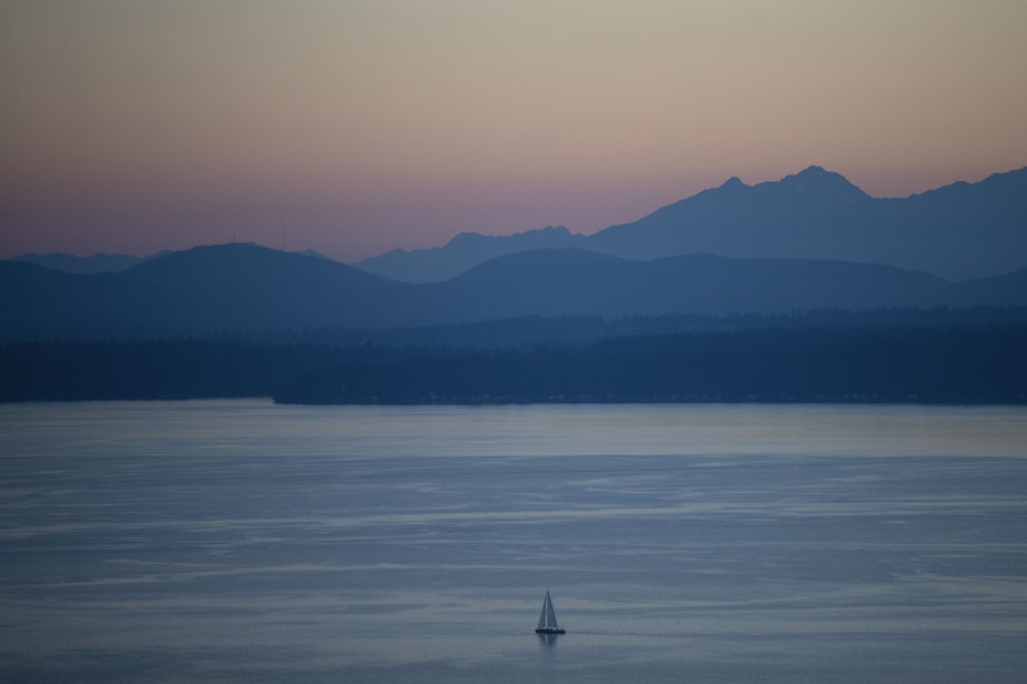 caption: A sailboat is shown in Elliott Bay as the sun sets on Monday, July 26, 2022, in Seattle. Temperatures are expected to reach 90 degrees this week in the Seattle area. 