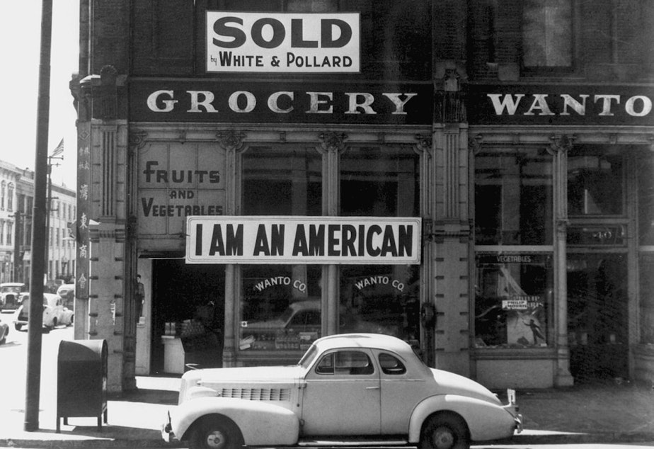 caption: A large sign reading "I am an American" is displayed in the window of a Japanese-owned grocery store, the day after the attack onPearl Harbor.