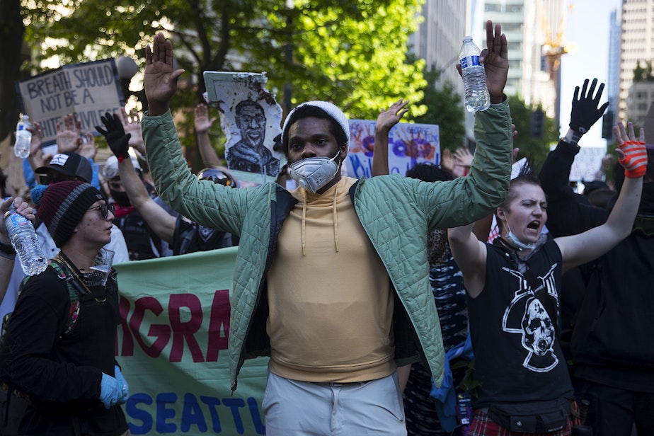 caption: David Lewis holds his hands in the air while leading a peaceful protest march on Monday, June 1, 2020, toward the Seattle Police Department East Precinct in Seattle. 