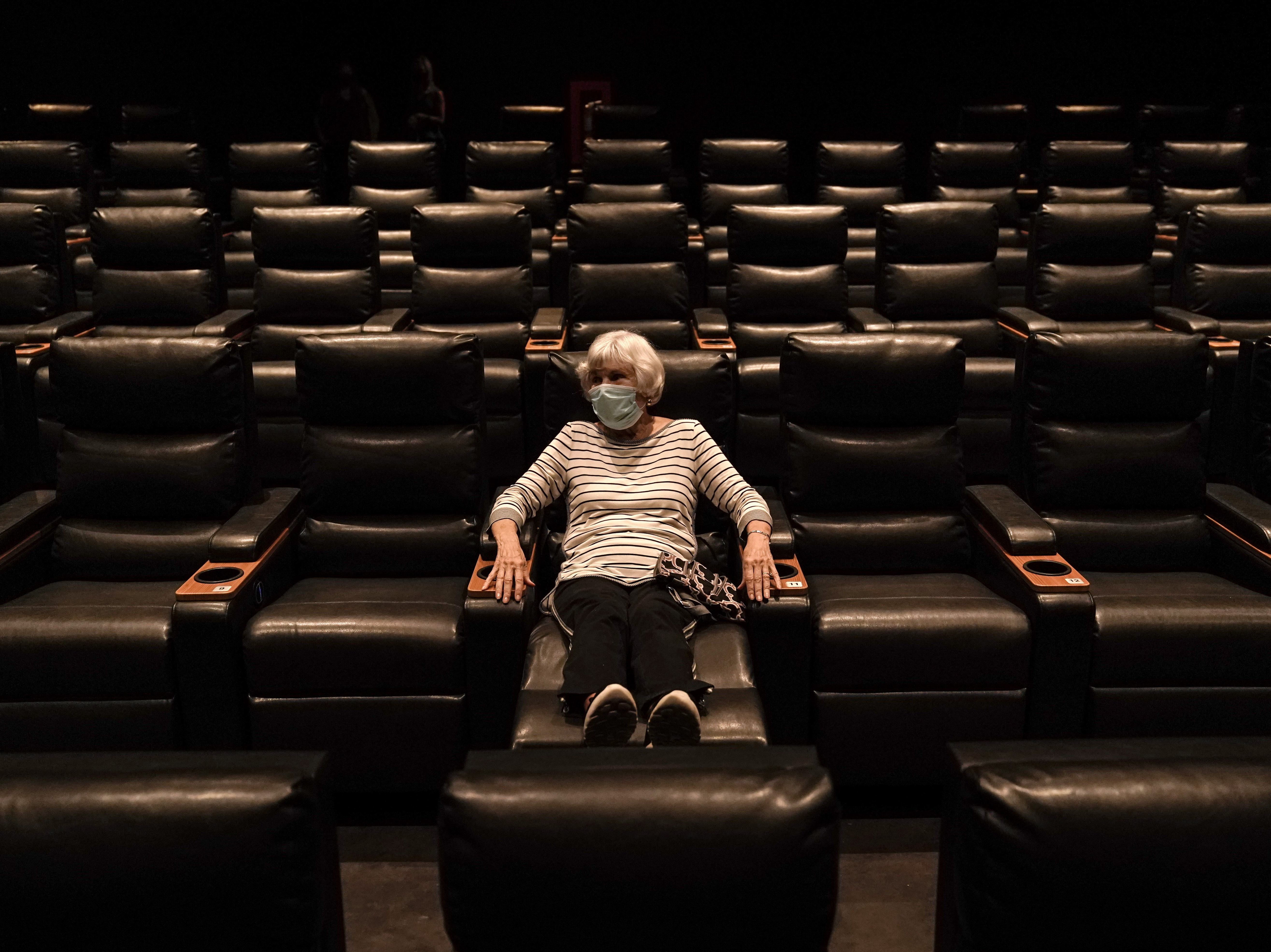 caption: A woman sits in a theater in Irvine, Calif., waiting for a movie to start, on Sept. 8. A COVID-19 vaccine could unleash pent-up spending from households that have mostly avoided activities like going to the gym during the coronavirus pandemic.