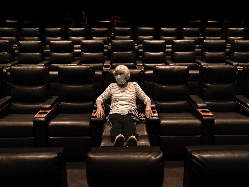 caption: A woman sits in a theater in Irvine, Calif., waiting for a movie to start, on Sept. 8. A COVID-19 vaccine could unleash pent-up spending from households that have mostly avoided activities like going to the gym during the coronavirus pandemic.