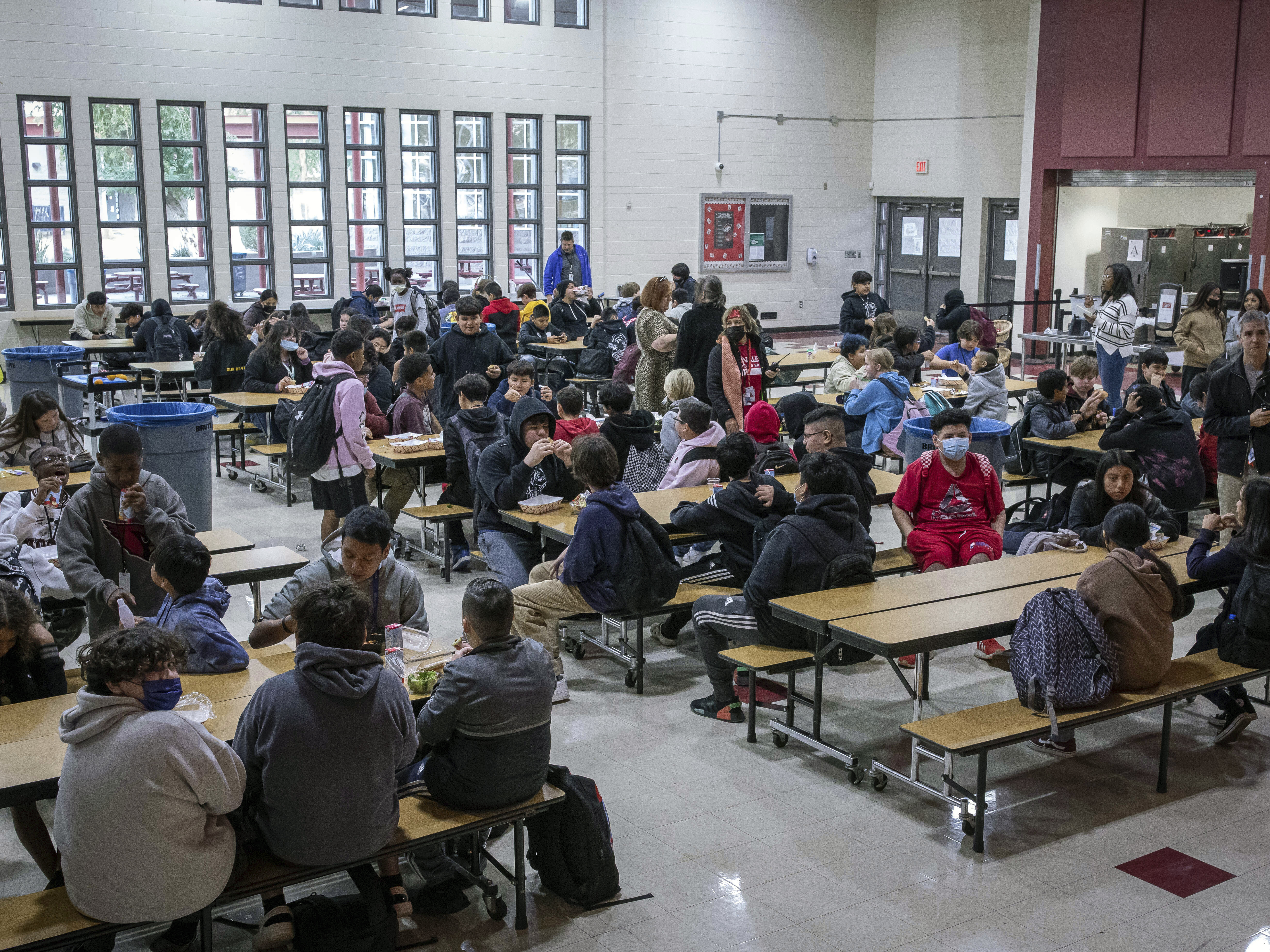 caption: Students eat lunch in the cafeteria at Tonalea K-8 school in Scottsdale, Ariz., on Dec. 12, 2022. In Massachusetts, a new 4% state income tax on incomes above $1 million will help pay for free school lunches.