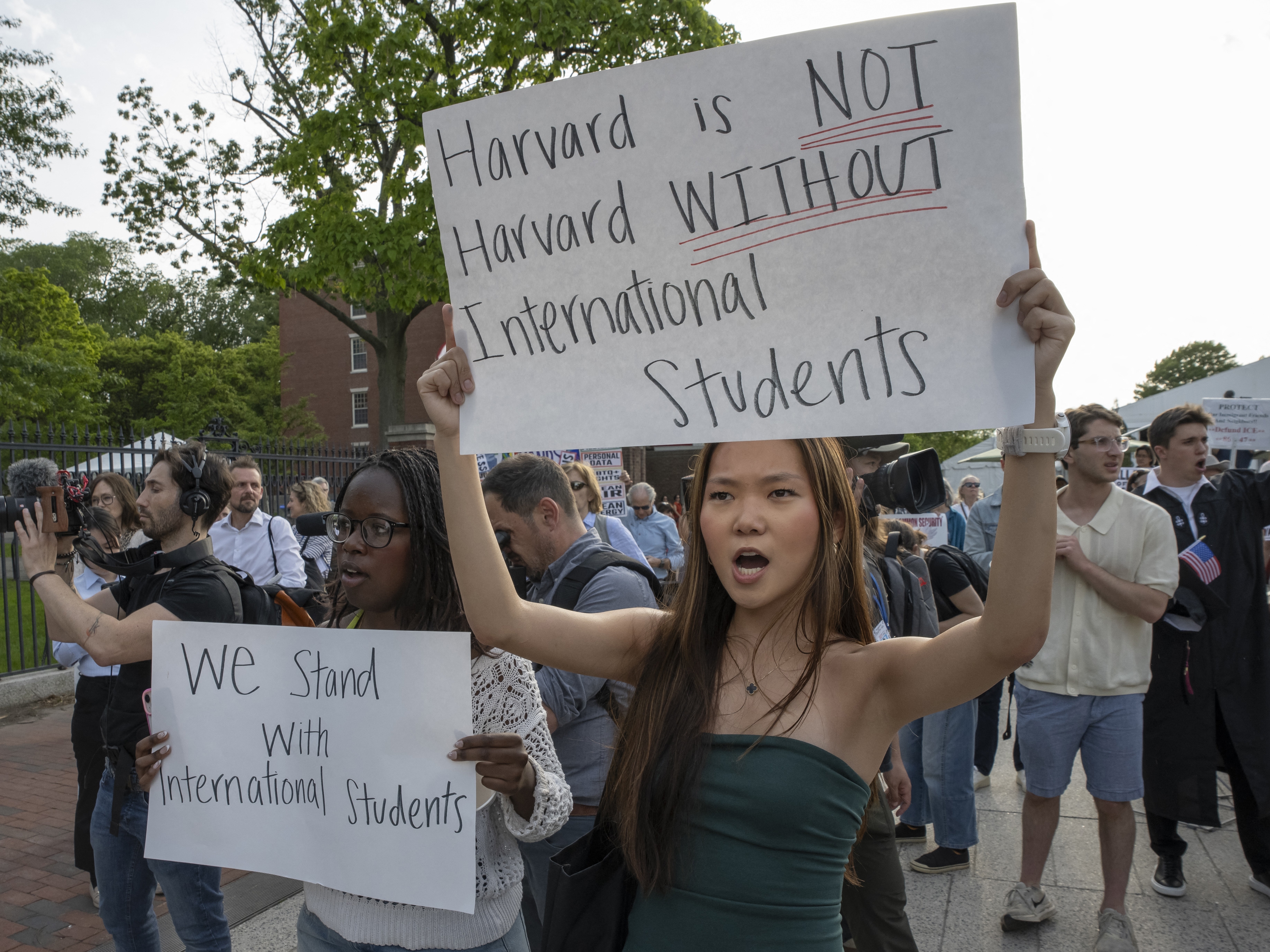 caption: People hold up signs during the Harvard Students for Freedom rally in support of international students at the Harvard University campus in Boston on May 27.