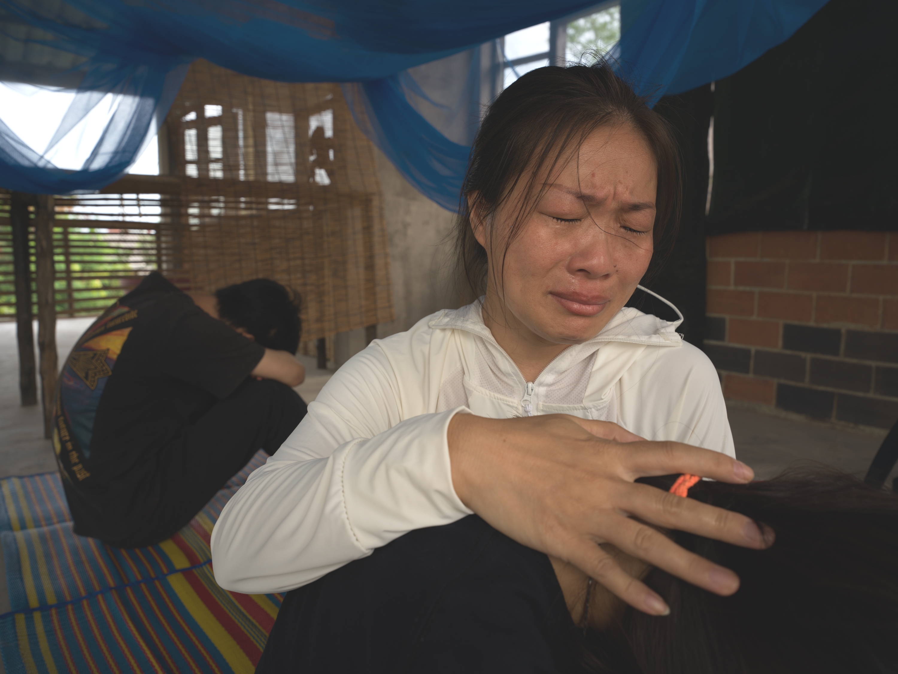 caption: Liu Fengling comforts her daughter and son in Bangkok after spending four months in detention.