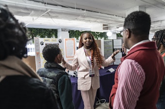 caption: At the National STEM Festival, 12th-grader Treyonna Sullivan talks with visitors about her "Project Poop," created to encourage pet owners in her community to dispose of their pet's waste.