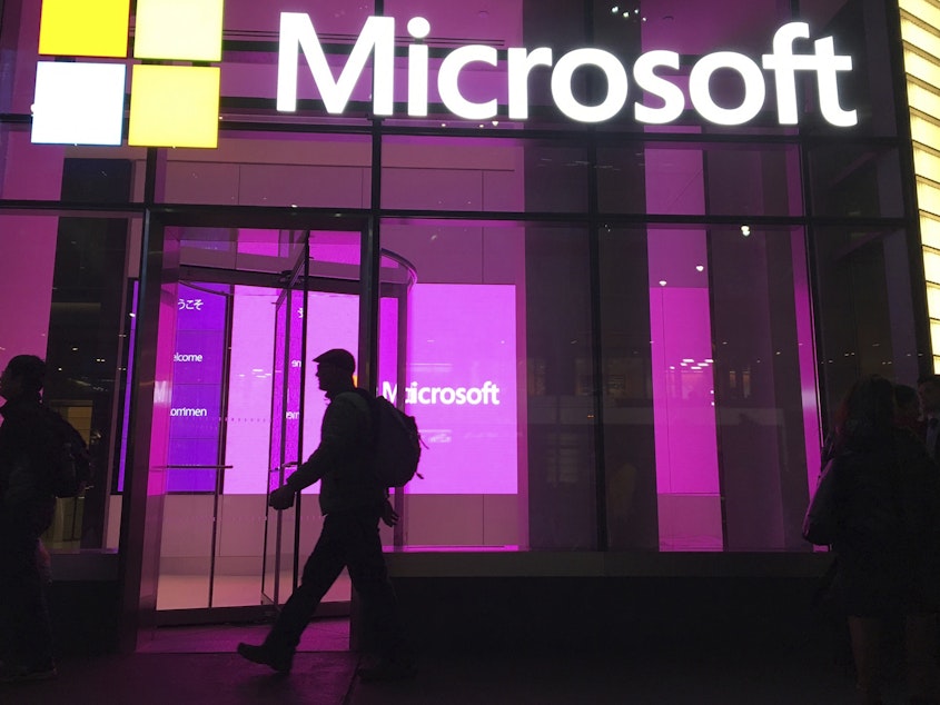 caption: People walk past a Microsoft office in New York in 2016. Big Tech companies, like Google and Microsoft, and dozens of smaller startups have collectively shed more than 20,000 workers so far this year.