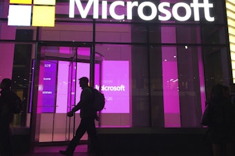 caption: People walk past a Microsoft office in New York in 2016. Big Tech companies, like Google and Microsoft, and dozens of smaller startups have collectively shed more than 20,000 workers so far this year.