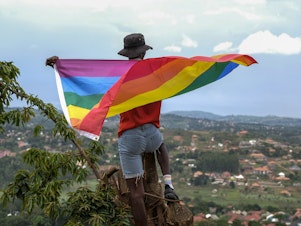 caption: A gay Ugandan man holds a pride flag as he poses for a photograph in Uganda in March.