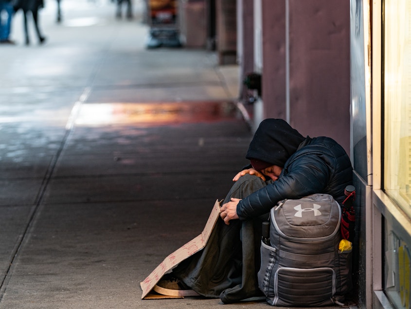 caption: A homeless person sleeps on a sidewalk near Time Square on December 10, 2019.