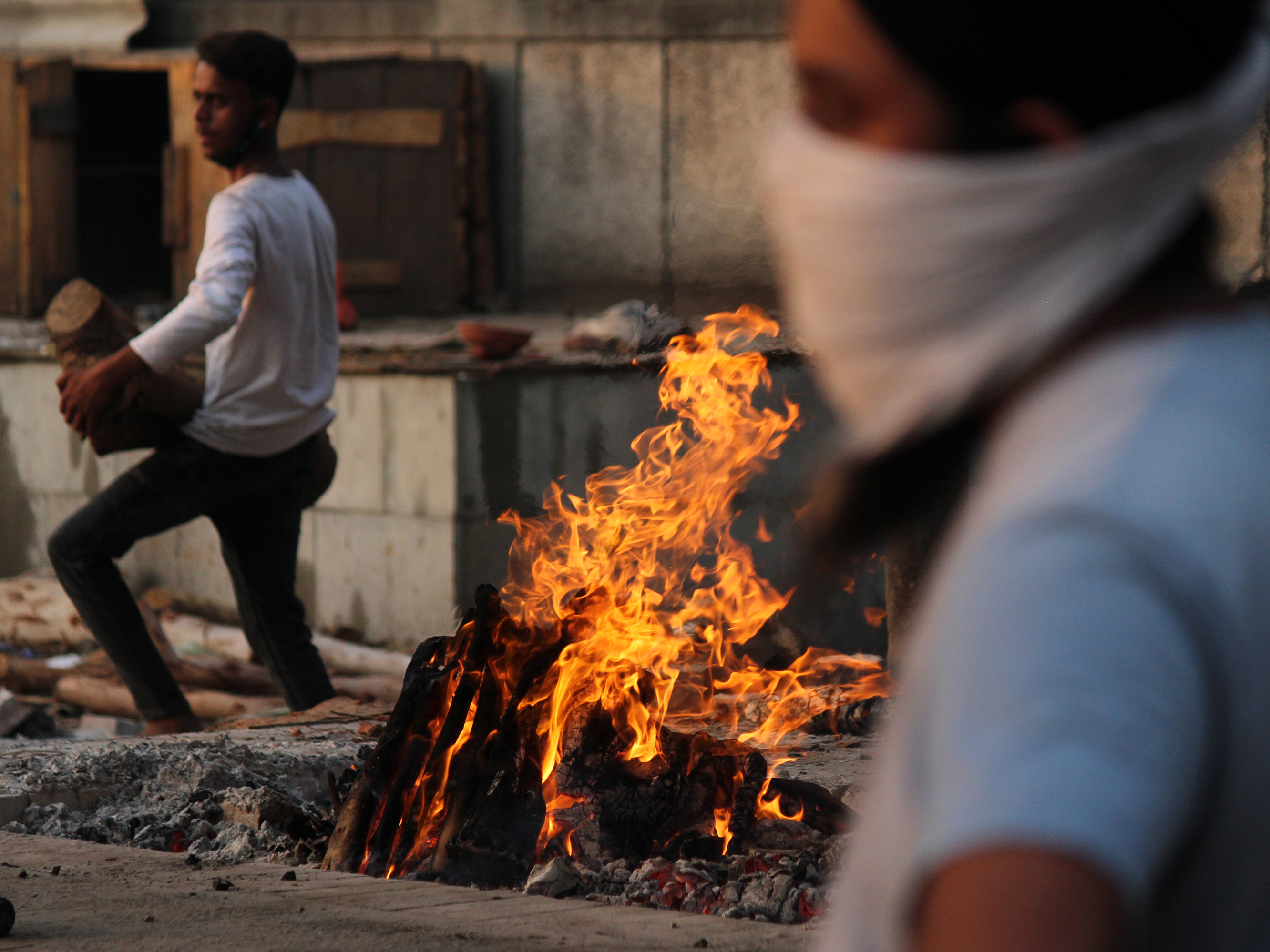 caption: In New Delhi on Monday, family members cremate the body of a person who died after contracting COVID-19.