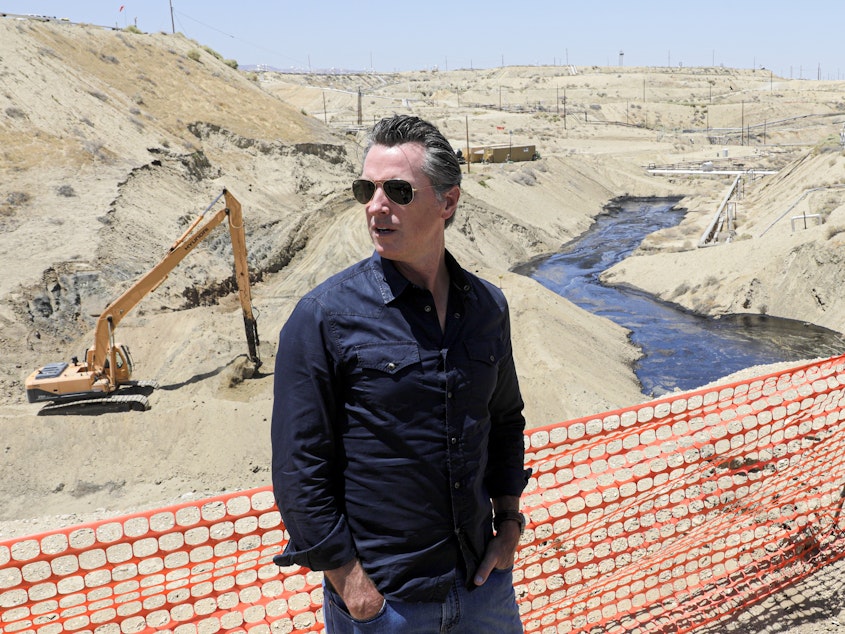 caption: Gov. Gavin Newsom tours the Chevron oil field west of Bakersfield, where a spill of more than 800,000 gallons flowed into a dry creek bed in McKittrick, Calif. in July 2019.