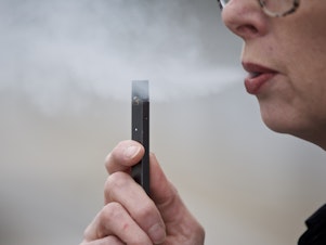 caption: A woman exhales a puff of vapor from a Juul pen in Vancouver, Wash. Television broadcasters including Viacom, CBS and WarnerMedia announced they are no longer running e-cigarette ads.