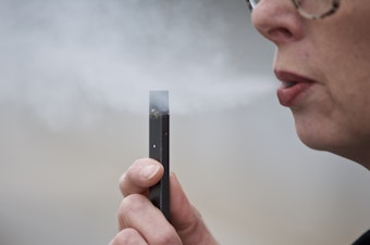 caption: A woman exhales a puff of vapor from a Juul pen in Vancouver, Wash. Television broadcasters including Viacom, CBS and WarnerMedia announced they are no longer running e-cigarette ads.