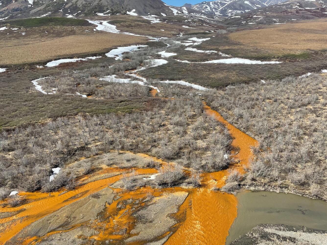 caption: The orange tributary of the Kugororuk River in Alaska is an example of a "rusting river." These rivers are increasingly common in the Brooks Range of northern Alaska, the result of thawing permafrost. The orange color is caused by naturally occurring iron, but it can also indicate elevated levels of heavy metals.