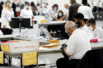 caption: Election workers count absentee ballots earlier this month in Detroit, the county seat of Wayne County, Mich.